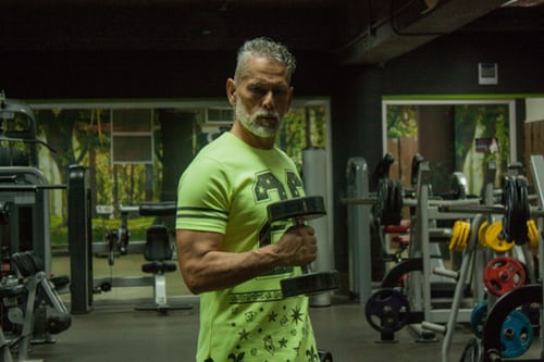 gespierde grijze man op leeftijd in groen shirt met halter